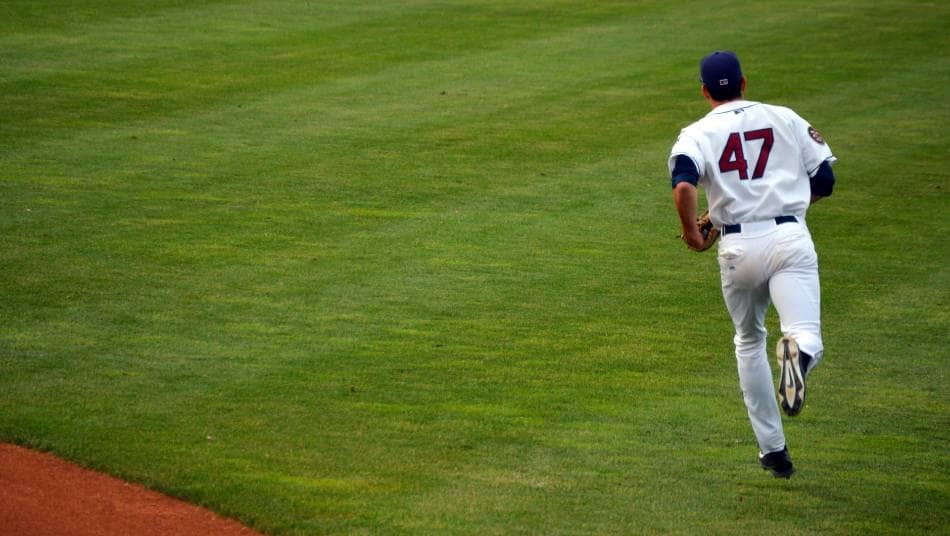 Baseball outfielder jogs out to his position.