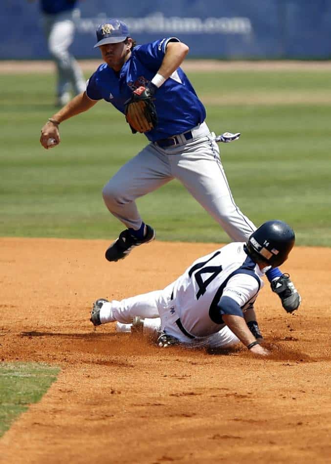 El infielder de béisbol salta sobre el corredor para intentar girar el juego doble.