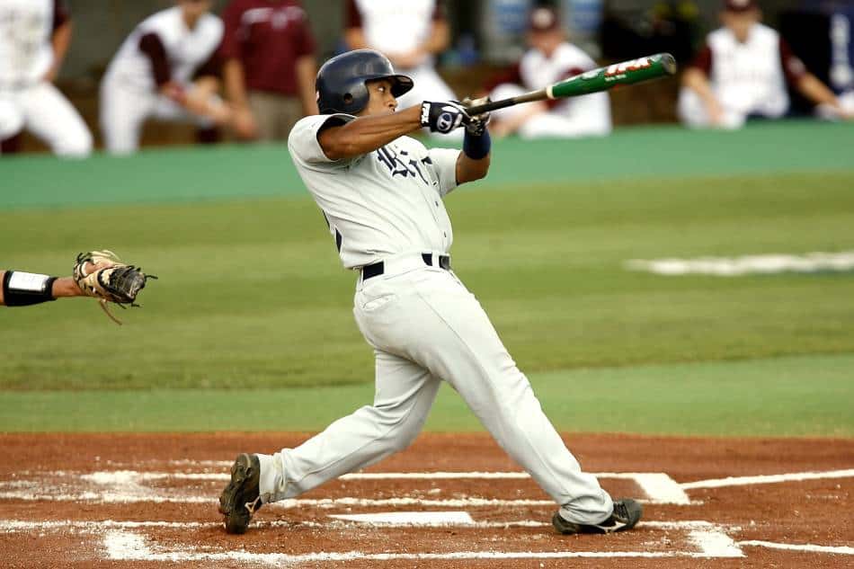 College baseball player swings at a pitch.