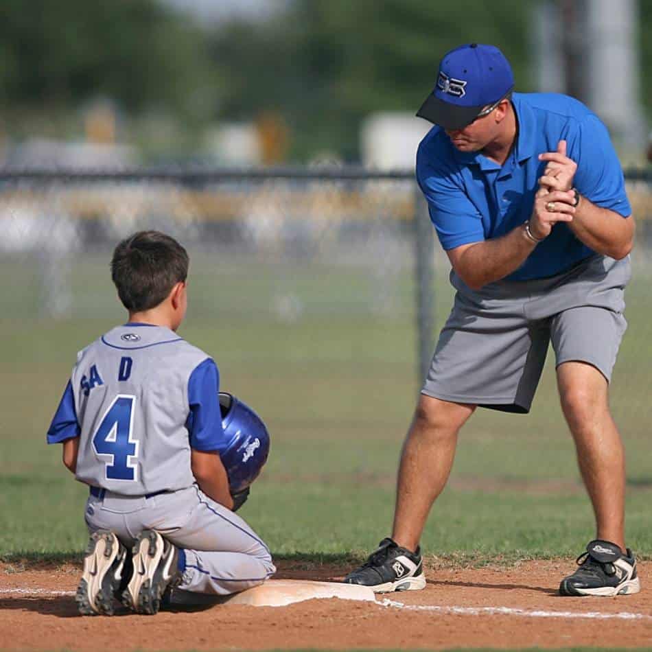 Młodzieżowy trener baseballowy pokazuje prawidłową postawę zawodnika.