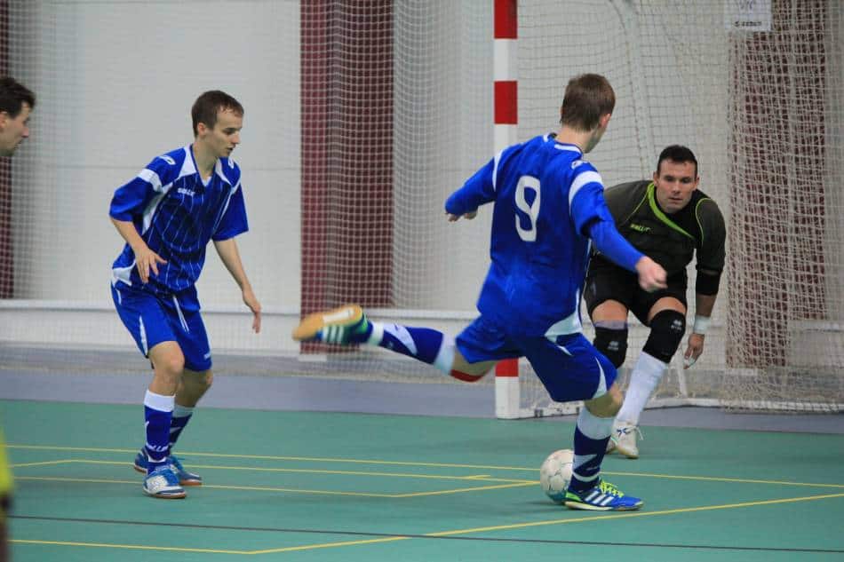 Soccer goalie looks to block a player's shot in indoor soccer.