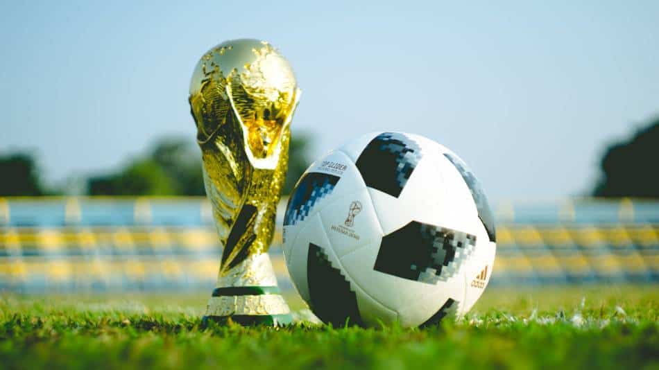 Soccer ball next to replica World Cup trophy.