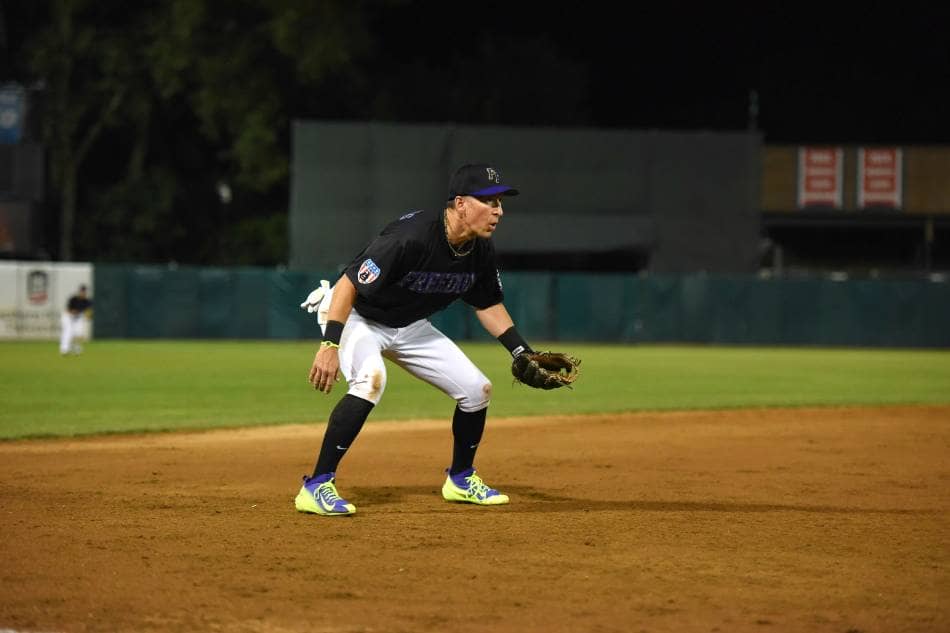 Baseball player gets in the ready position on the left side of the infield.