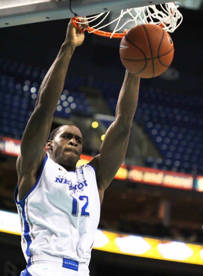 Basketball player in white and blue dunks the ball.