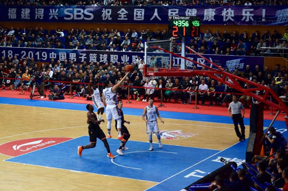 Basketball player in white lays up the basketball.