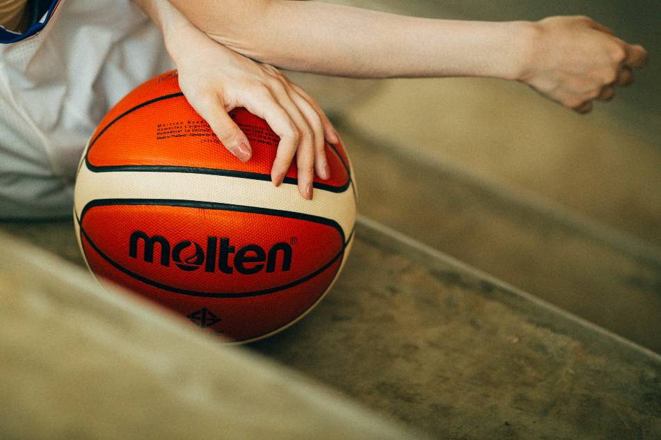 Woman holding a basketball in the bleachers.