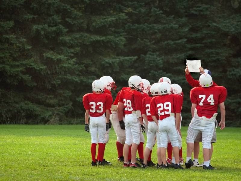  L'entraîneur de football des jeunes montre un jeu à son équipe.