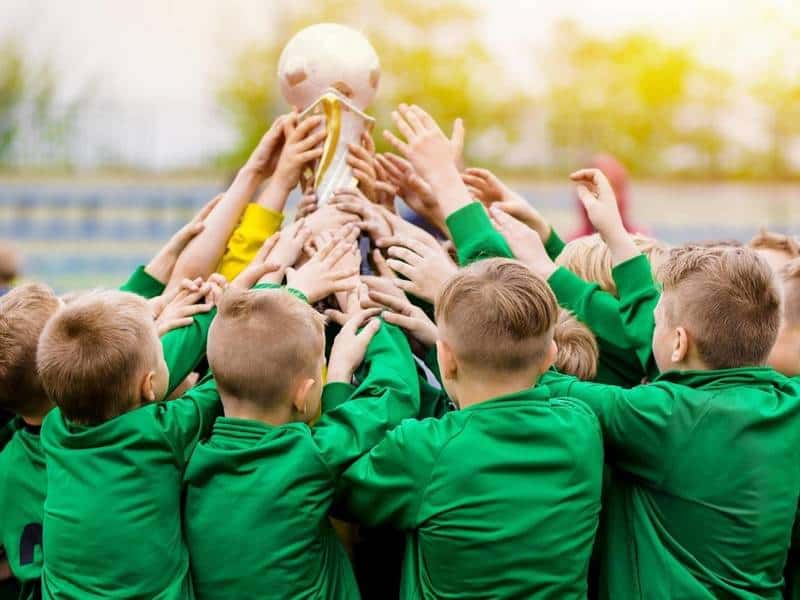 Equipe de futebol juvenil detém troféu.