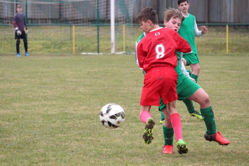 Two youth soccer players collide in pursuit of the ball.