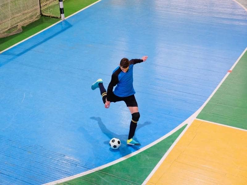 Soccer play kicks the ball in indoor soccer.