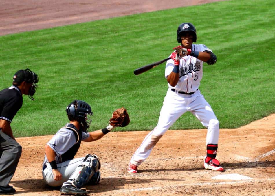 Minor league baseball player in white readjusts his hands on the bat after taking a pitch.