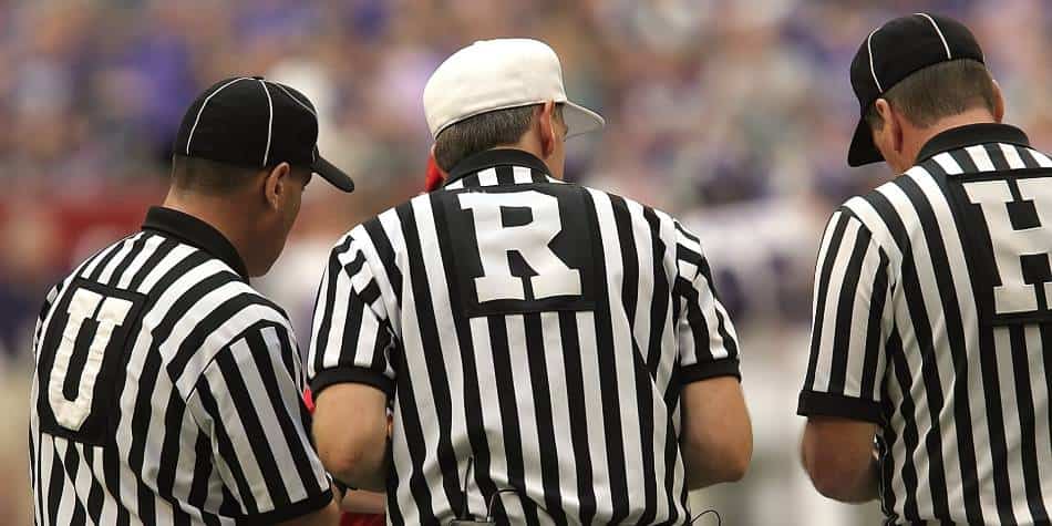 Football referees huddle to go over a call.