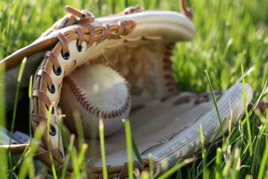 A baseball sits in a glove on the grass.