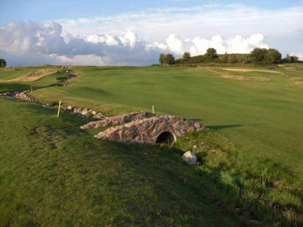 A small bridge connects two holes on a golf course.