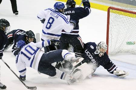 College hockey players battle near the net for the puck.