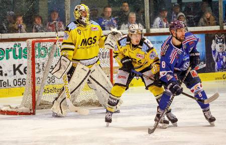 Two hockey players battle for position in front of the net.