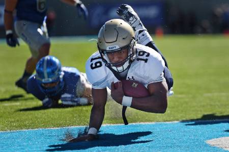 A college football player dives into the end zone.