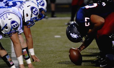 Both football teams line up at the line of scrimmage.