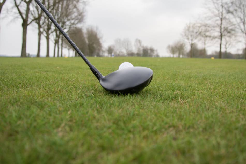 A golfer lines up his driver with the golf ball.