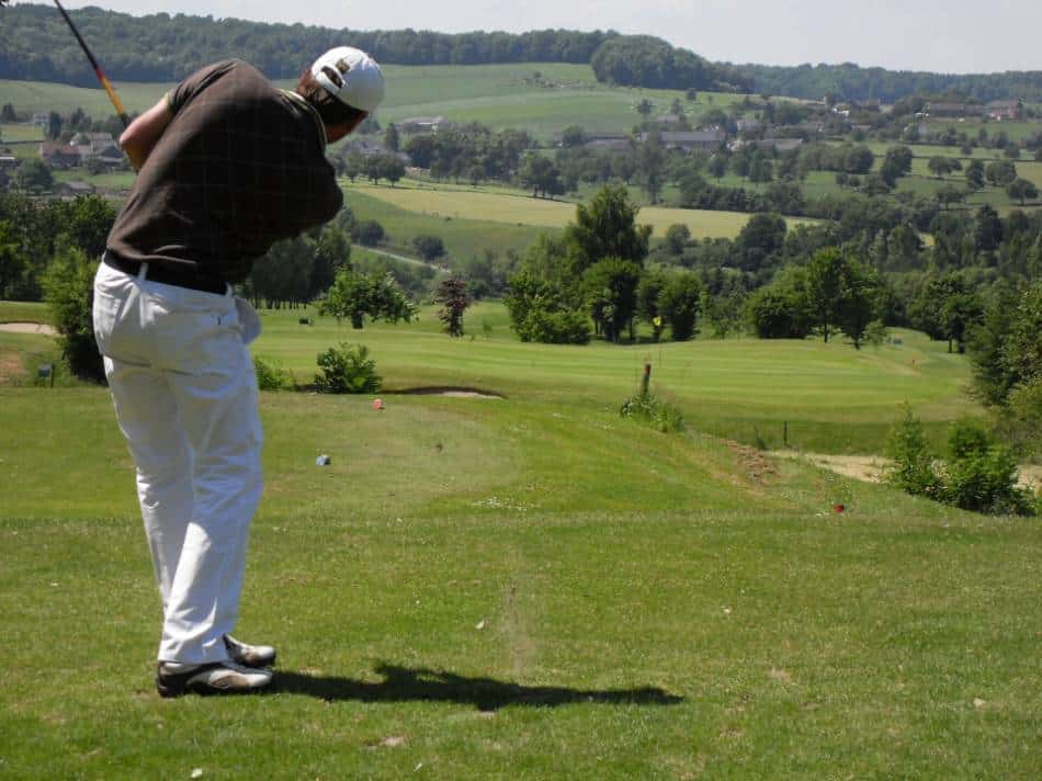 A golfer looks toward the hole after taking his swing.