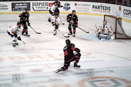 A professional hockey player goes down to one knee for a slapshot.