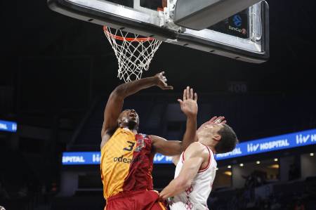 A professional basketball player in gold and red gets fouled during a shot.