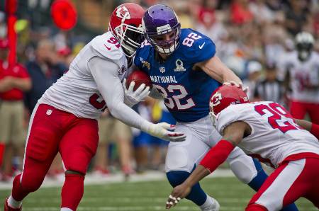 A Vikings player stiff arms a Chiefs player while getting tackled.