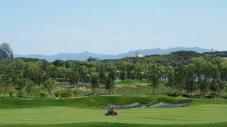 A lawnmower cutting the grass at a golf course.