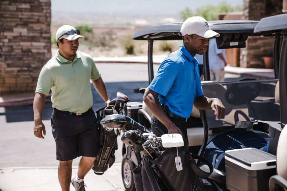 Two golfers walk toward their golf cart.