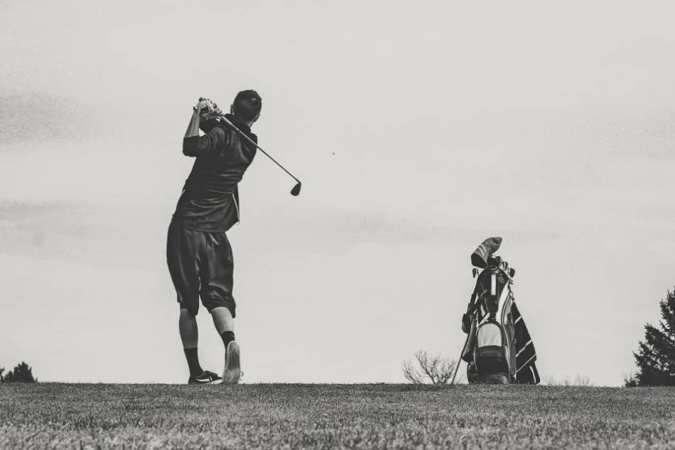 A golfer takes a swing with an iron.