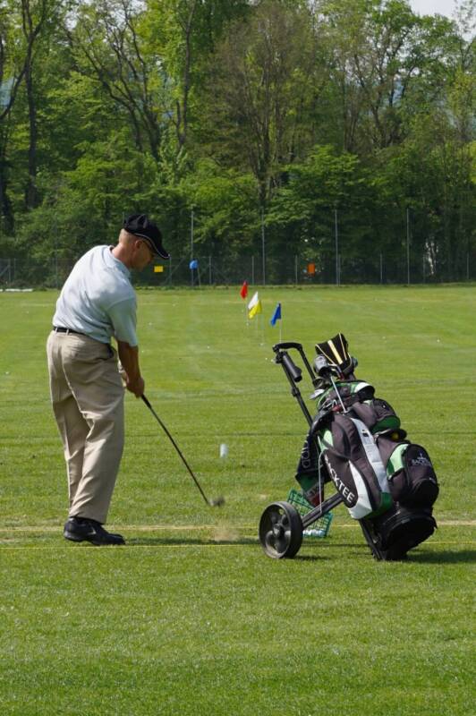 A golfer takes a swing with a hybrid at the driving range.