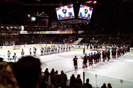 Two professional hockey teams line up at the blue lines for the national anthem(s).