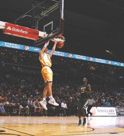 A college basketball player dunking the ball.