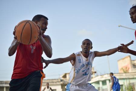 A basketball player putting his hand out to defend against the player with the ball.