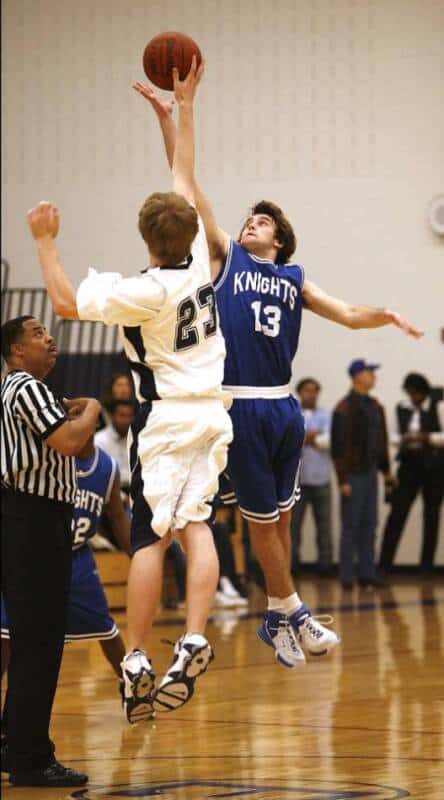 Two high school basketball players jumping for a jump ball.