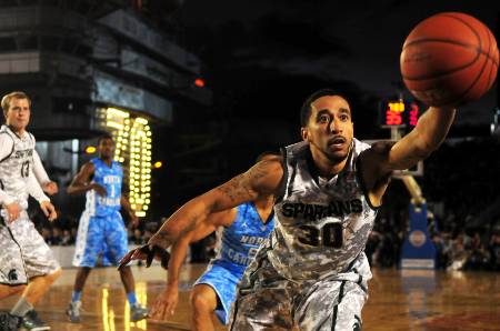 A college basketball player tries to keep the ball in bounds.