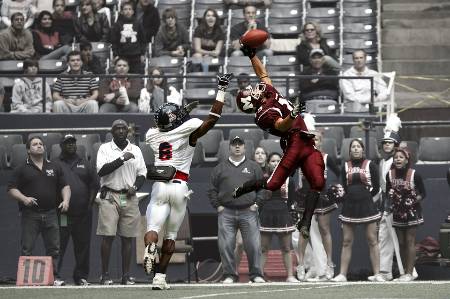 A college football player makes a one-handed catch in the red zone.