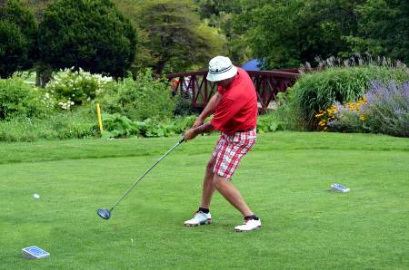 A left-handed golfer teeing off.