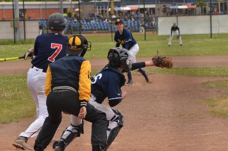 A catcher stands up to reach an outside pitch.