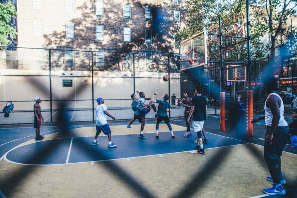 Basketball players fight for a rebound on an outdoor court.