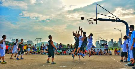 A basketball player commits an over the back foul while going for a rebound.