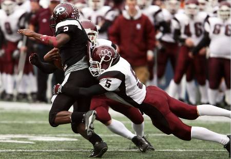 A college receiver gets tackled by two defenders.