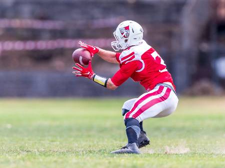 A high school football player catches the ball during a wheel route.