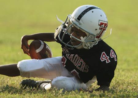 A Pee Wee football player fumbles the ball.