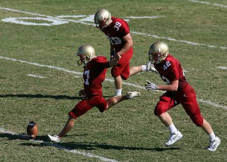 The football team in red attempts a squib kick.