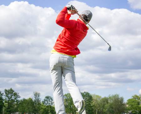 A golfer holds their follow through after taking an iron shot.