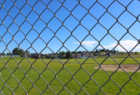 A baseball field as seen threw a chain-linked fence.