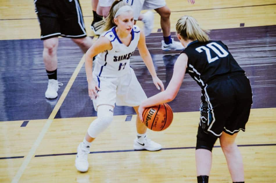 A girl's high school basketball player sizes up her defender near the key.