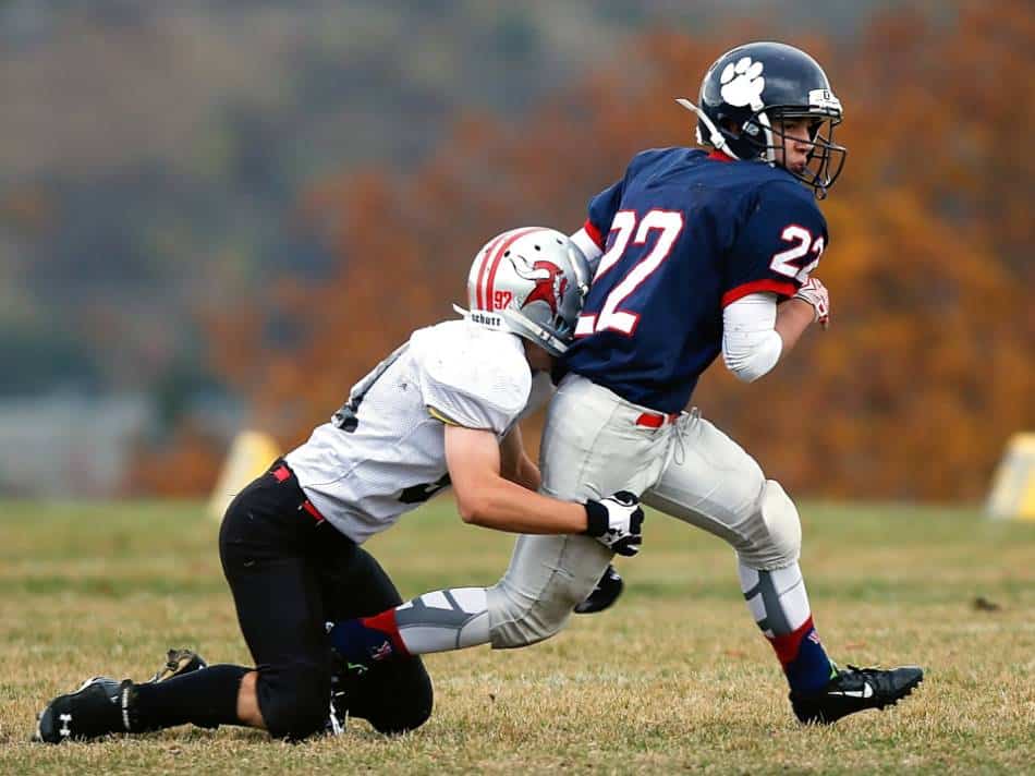 A football wide receiver tries to evade a tackle on an in route.