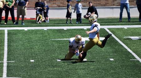 A college football player attempts a free kick.